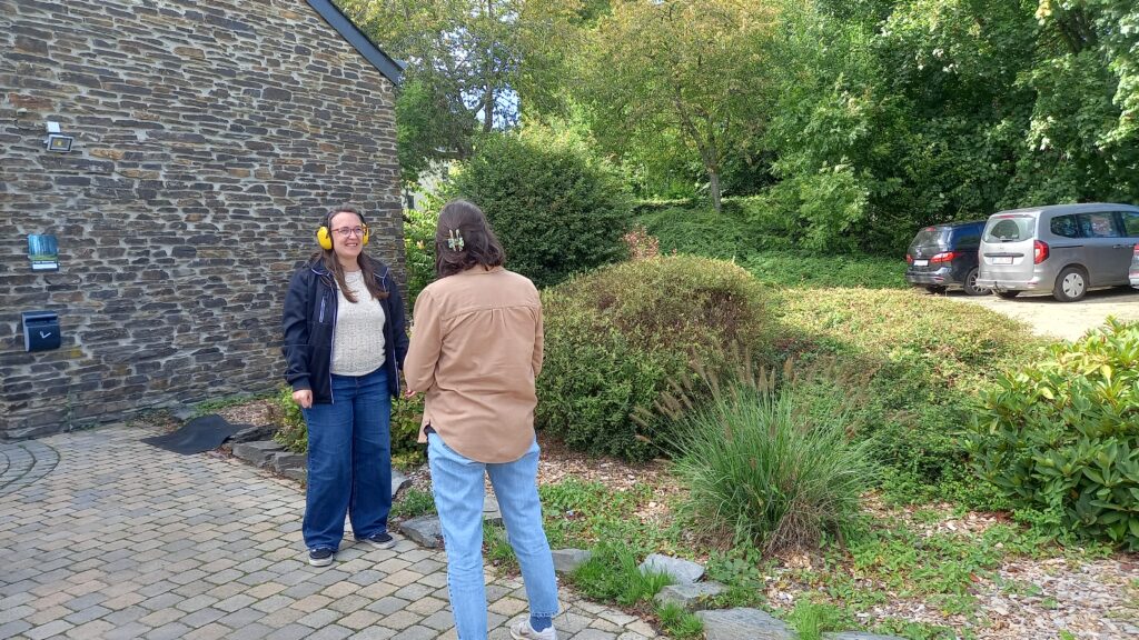 Deux personnes essaient de se comprendre lors d'une mise en situation "personne mal entendante", une personne porte un casque anti-bruit